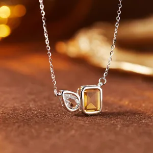 Close-up of silver necklace with teardrop white topaz and rectangular citrine pendant.