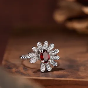 Makrodetail eines eleganten s925 Silber Gänseblümchenrings mit ovalem rotem Granatstein