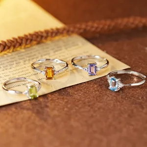 Macro view of four S925 silver rings featuring emerald-cut colorful natural gemstones.