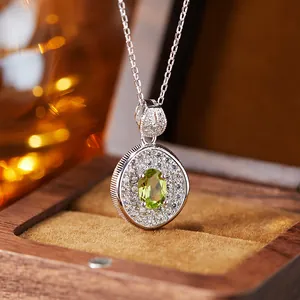 Silver pendant with oval green gemstone and white pave stones in a luxury wooden box