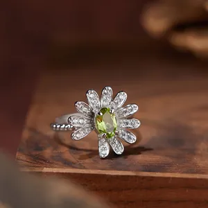 Detailaufnahme eines silbernen Gänseblümchen-Rings mit ovalem Peridot und Kristallen