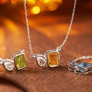 Macro detail of S925 silver necklace featuring pear and emerald cut gemstones.