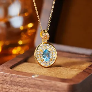Macro detail of oval blue topaz pendant with gold-plated silver chain and pavé stones