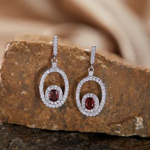 Macro view of silver drop earrings with red oval garnet gemstones on a rock base
