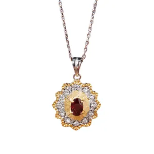 Macro view of vintage gold flower pendant featuring a central red garnet gemstone.