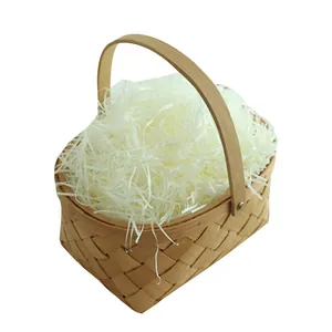 White shredded raffia paper filler in a small woven wood basket for gift boxes