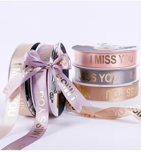 Detail van luxe satijnen linten met gouden I MISS YOU tekst voor cadeauverpakking