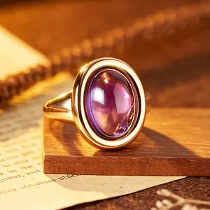 Detailed macro view of a gold-plated amethyst ring featuring a large purple cabochon stone.