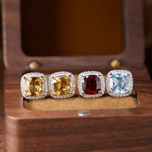 Close-up of four natural gemstone Diana style halo rings displayed in a wooden box