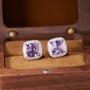Close-up of cushion-cut amethyst earrings in a silver halo setting inside a wooden box