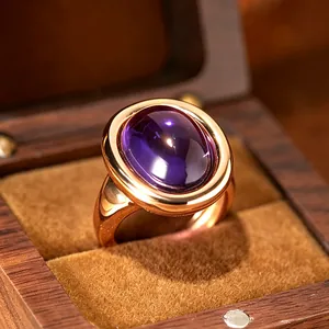 Macro view of a 24K gold plated ring featuring a polished oval amethyst gemstone