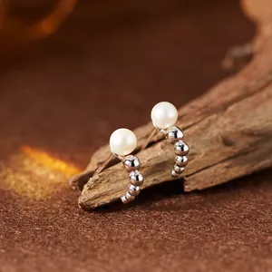 Detailaufnahme von S925 Sterling Silber Ohrsteckern mit Naturperlen auf einem Holzständer.