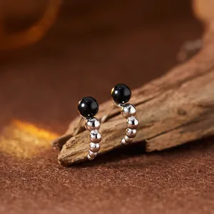 Exquisite Nahaufnahme von Ohrsteckern aus schwarzem Achat und Sterlingsilber auf Holztextur
