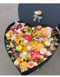 Detailed view of a heart-shaped gift box filled with tropical fruits and roses.