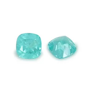Primo piano di due pietre preziose YAG color Paraiba con taglio a cuscino su sfondo bianco.
