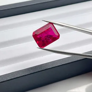 Detailed macro shot of an emerald cut lab-grown red ruby gemstone held by tweezers (82 chars)