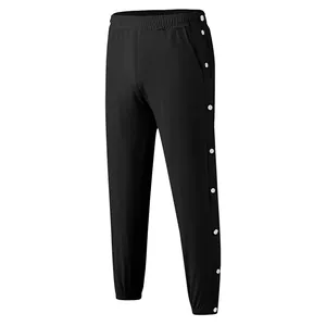 Detailweergave van zwarte sportbroek met drukknopen aan de zijkant en elastische enkelmanchetten
