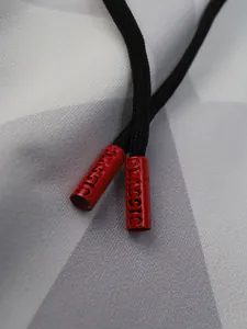 Détail macro du cordon de serrage noir avec embouts rouges embossés classic sur pantalon sport