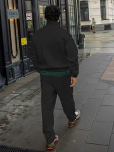 Back view of men's black ribbed tracksuit with stand-collar jacket in urban street setting