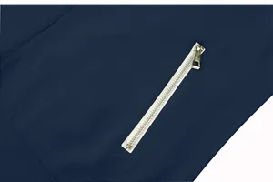 High-quality close-up detail of golden zipper on navy blue jacquard lattice textured fabric garment