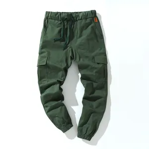 Detailed close-up of dark green cotton cargo pants featuring a drawstring waist and pockets