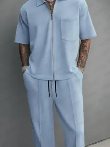 Detail of light blue men's two-piece set with zip-up polo and matching trousers.