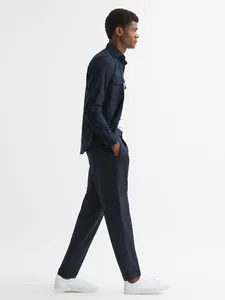 Side profile view of a man wearing a navy blue casual shirt jacket and trousers