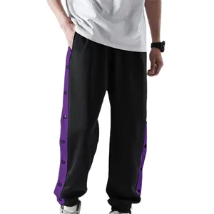 Detail van zwarte herenjoggingbroek met paarse drukknoopsluiting aan de zijkant