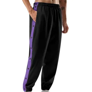 Detail van zwarte sportbroek met paarse zijstrepen en handige drukknopen