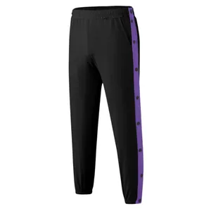 Detail van zwarte joggingbroek met paarse zijstrepen en handige drukknoppen