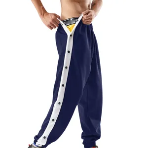 Detail van donkerblauwe sportbroek met witte zijstrepen en drukknopen.