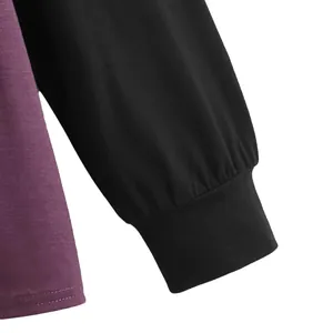 Detail shot of ribbed cuff and layered purple fabric on a black long-sleeve shirt.