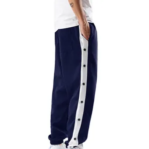 Detail van de donkerblauwe heren sportbroek met witte zijstrepen en zwarte drukknopen.
