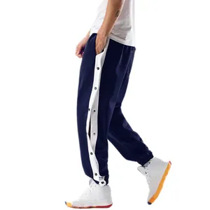 Detail van blauwe sportbroek met witte zijstrepen en functionele drukknopen aan de zijkant.