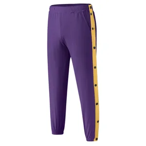 Detailweergave van paarse sportbroek met gele zijstrepen en drukknopen.