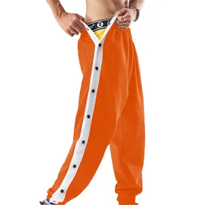 Detailopname van oranje heren sportbroek met drukknopen aan de zijkant en streep.