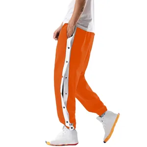 Gedetailleerde weergave van oranje herenjoggingbroek met drukknopen aan de zijkant