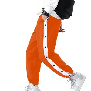 Detail van oranje heren sportbroek met witte zijstreep en functionele drukknoopsluiting
