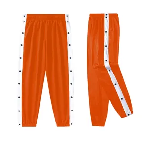 Feloranje sportbroek met drukknopen, witte zijstrepen en zijsplitten aan de kant.