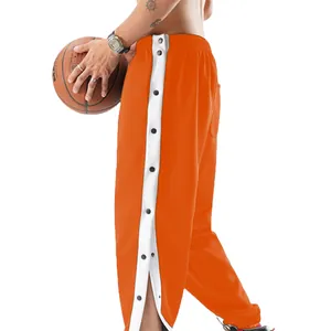 Detail van de oranje sneldrogende sportbroek met drukknopen aan de zijkant en een split.