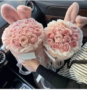 Close-up view of two pink rose bouquets in plush bunny ear hug buckets for Valentine's Day