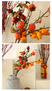 Detalle de ramas de frutas artificiales realistas con caquis y granadas decorativas.