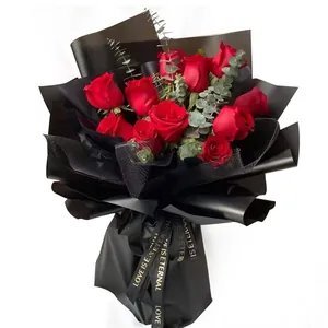 Élégant bouquet de roses rouges enveloppé dans un papier noir mat avec ruban romantique.