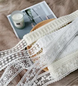 Close-up macro view showing various patterns of white embroidered floral lace ribbon