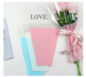 Close-up of LOVE. printed cellophane flower sleeve with pink roses and ribbon