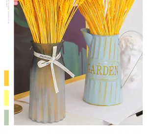 Beautiful golden dried wheat stalks displayed in decorative glass and vintage metal garden vases