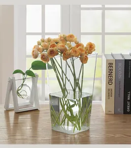 Macro view of transparent acrylic flower bucket holding fresh orange roses on wooden table