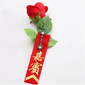 Close-up of a decorative red rose boutonniere featuring a magnetic clasp and guest ribbon.