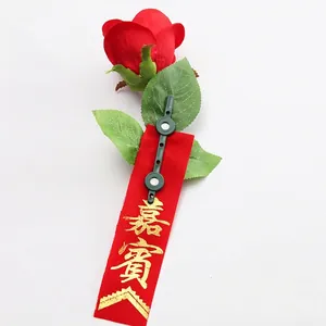 Artificial red rose boutonniere with guest ribbon and green magnetic clip for weddings