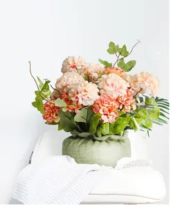 Detalle de flores de hortensia artificiales en una cesta decorativa de calabaza de yute.